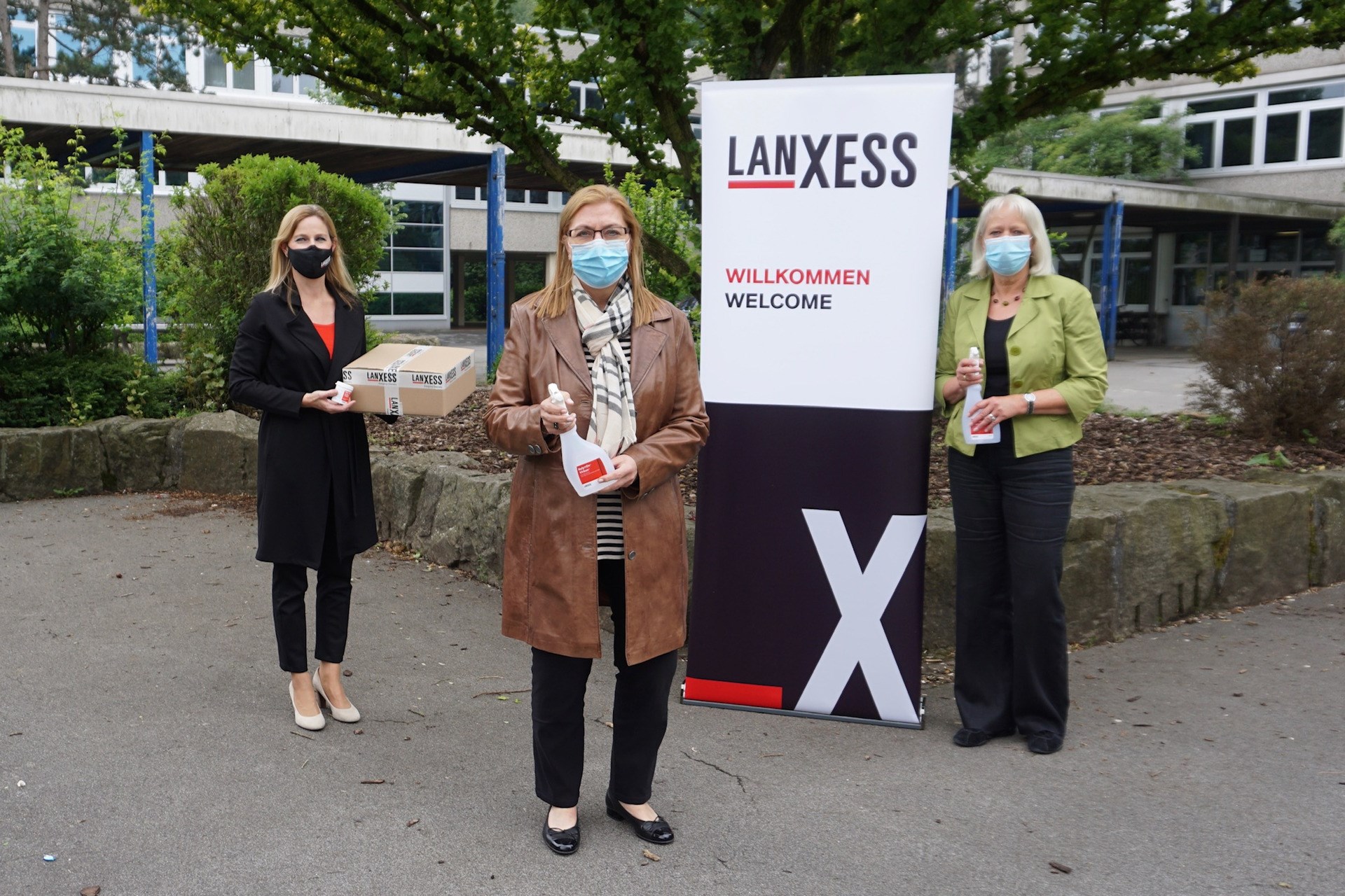 Nina Hasenkamp (from left to right), head of the LANXESS education initiative, hands over a package containing the disinfectant Rely+On Virkon, representing all schools in Bergkamen, to Christine Busch, head of the Bergkamen City School Board, and Bärbel Heidenreich, head of the Bergkamen Municipal High School.