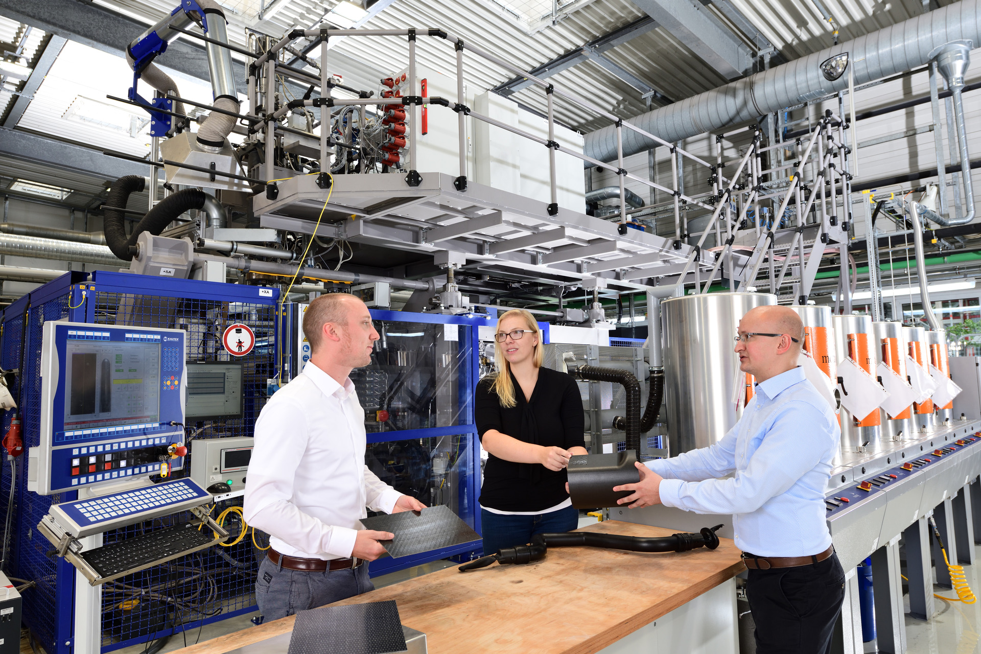 LANXESS HPM Technical Center, HPM experts in front of blow molding machine, blow molded part with Tepex reinforcement, from left to right: Tilmann Sontag, Loreen Winkeklhake, Arthur Rieb 