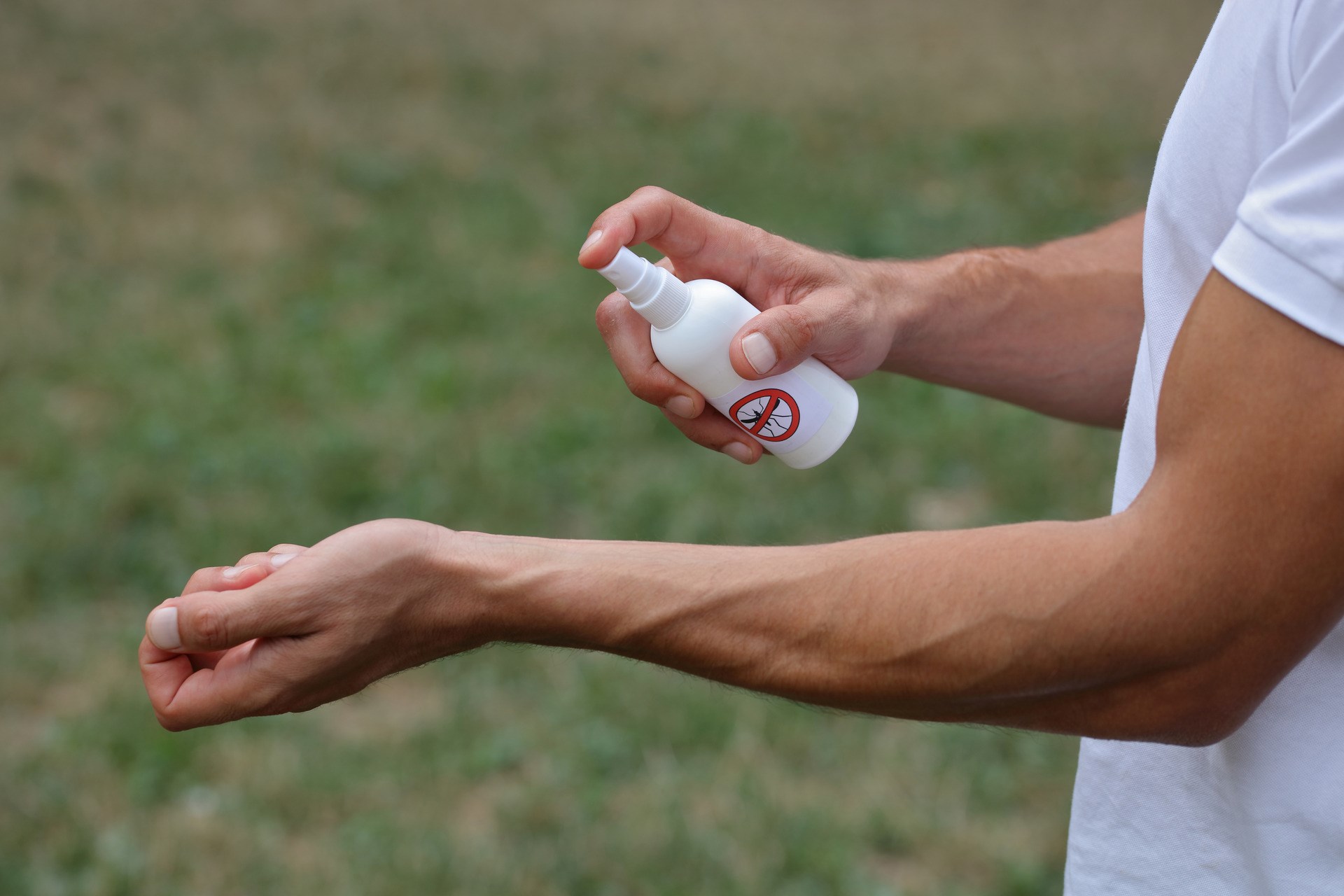 Mosquito repellent. Man using insect repellent spray outdoors.
