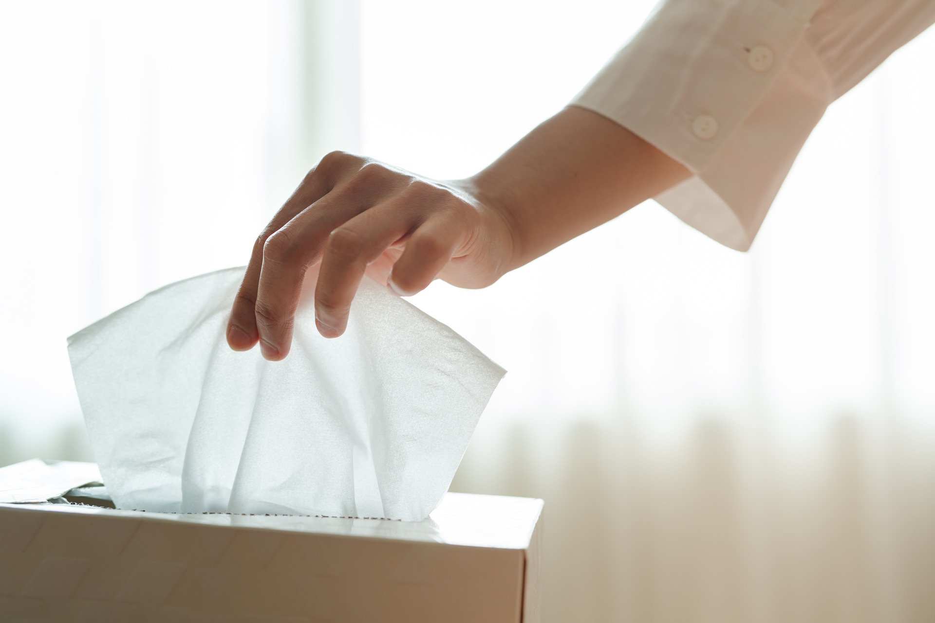 Female hand picking napkin/tissue paper from a tissue box