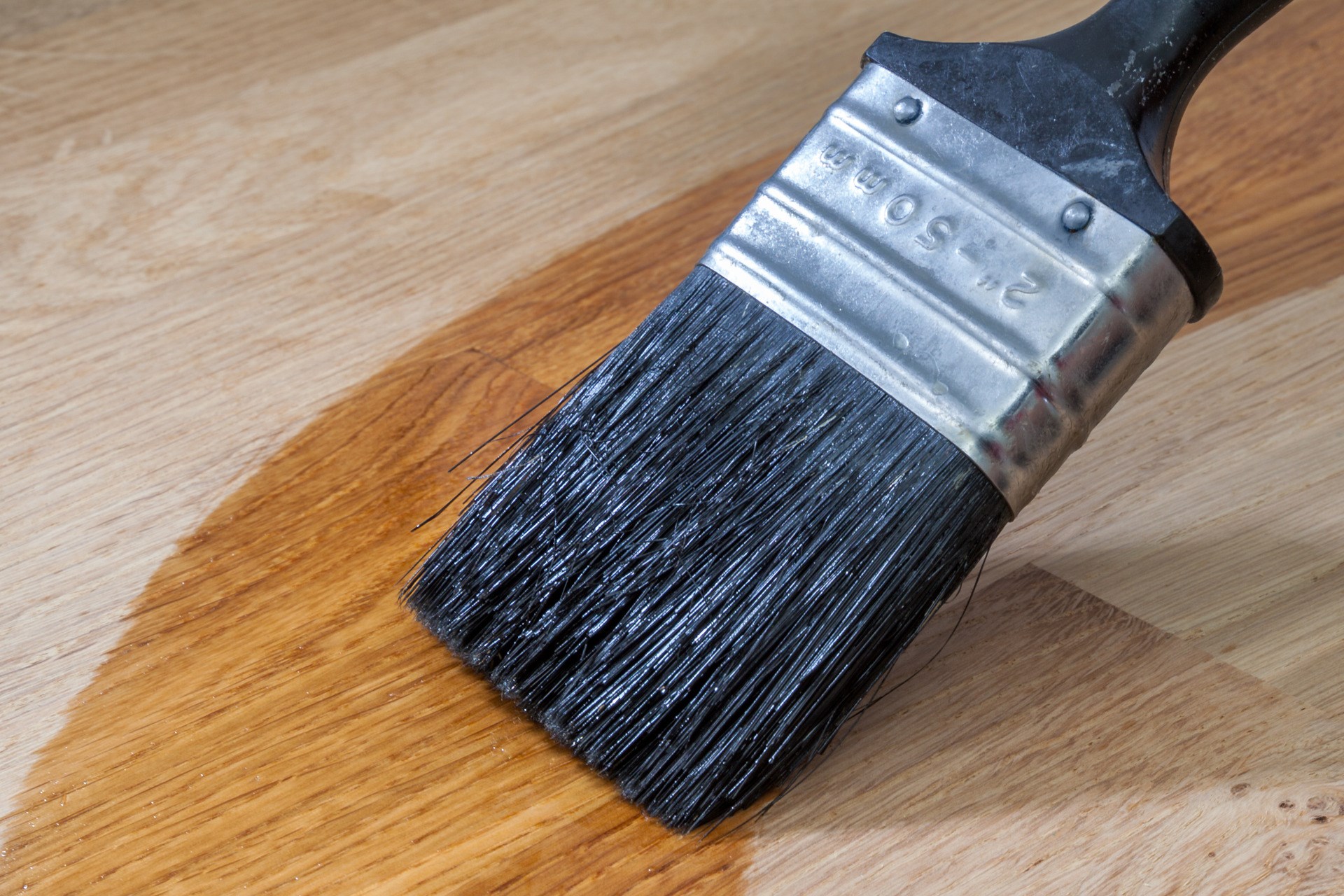 Close up of a paint brush that applyes wood oil onto a solid oak surface