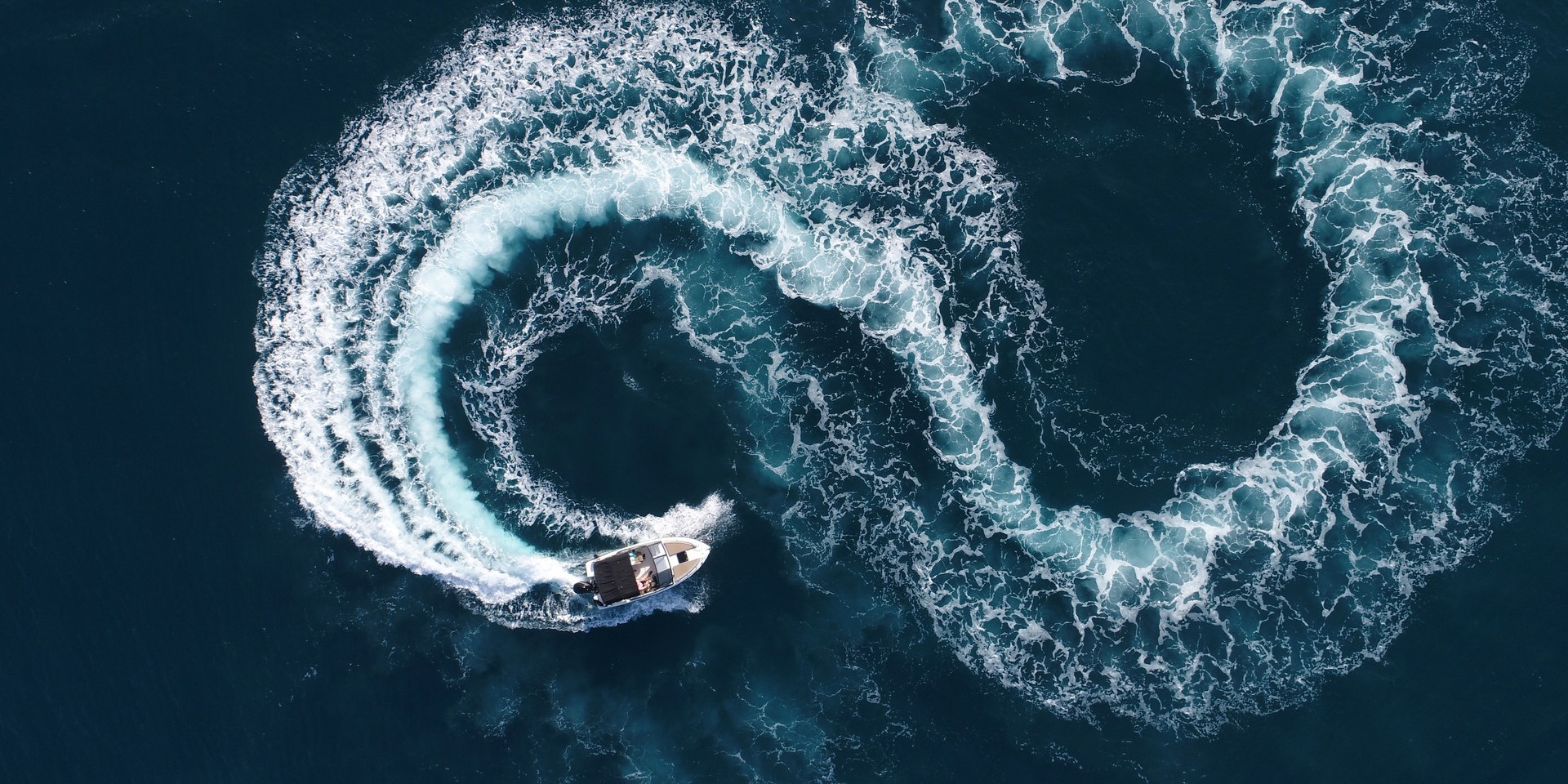 Luftaufnahme eines weißen Sportbootes an einem Sommertag. Motorboot drehen Schleife acht auf dem Meer machen metaverse Unendlichkeit Zukunft Konzept.