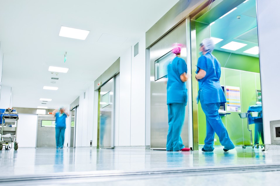 blurred figures wearing medical uniforms in hospital surgery corridor
