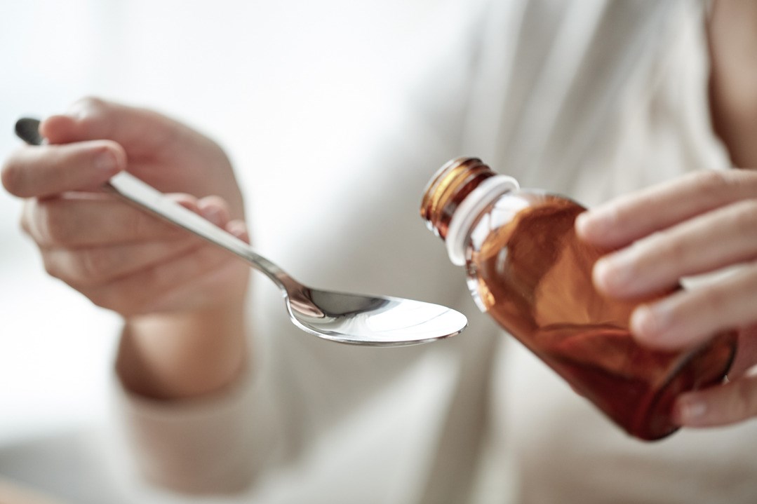 Woman pouring medication from bottle to spoon