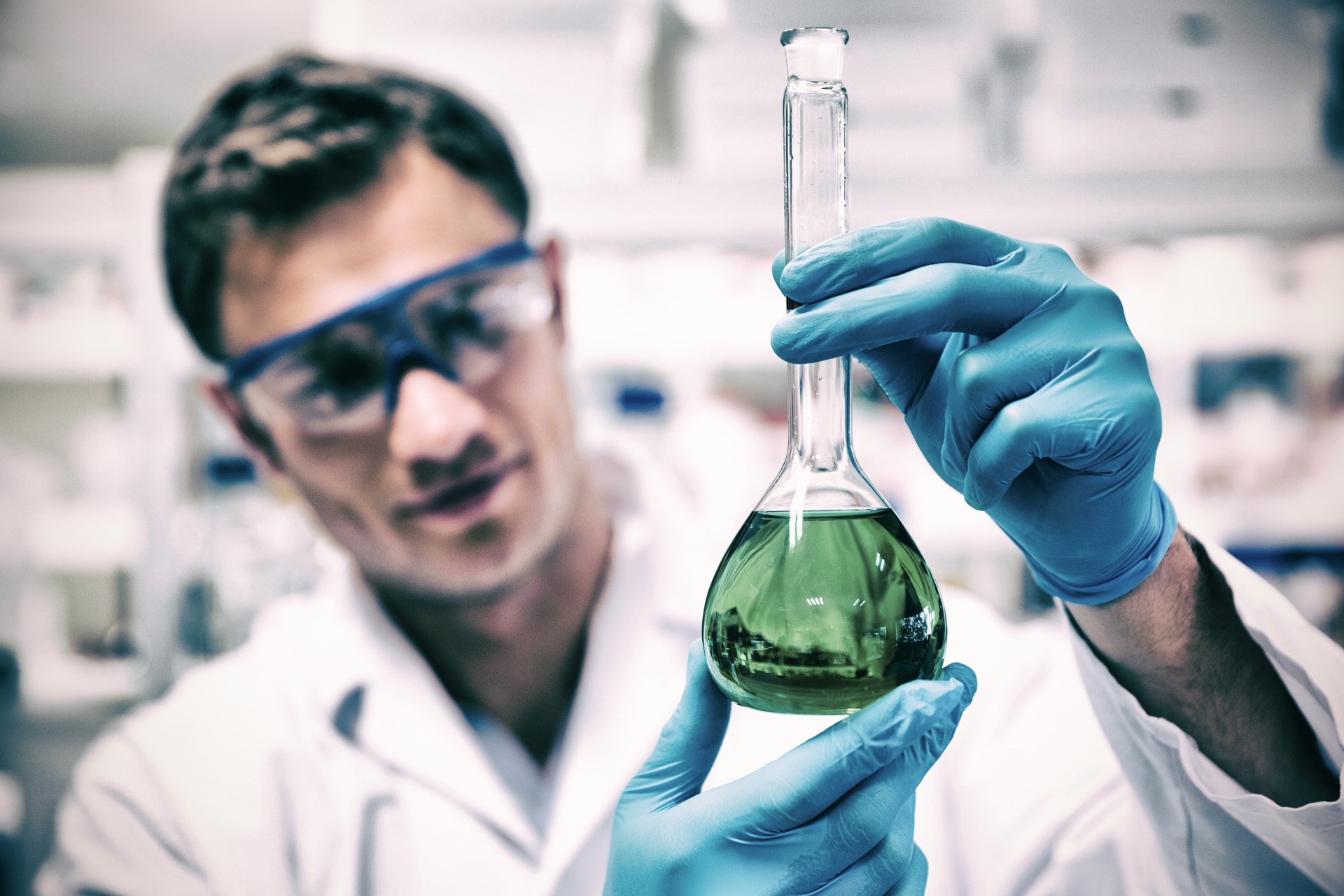 Chemist holding up beaker of green chemical
