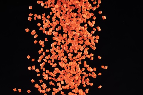 Orange Pocan plastic granules against a black background