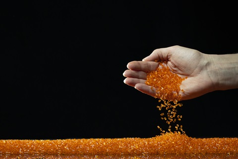 Hand holding orange Macrolex granules